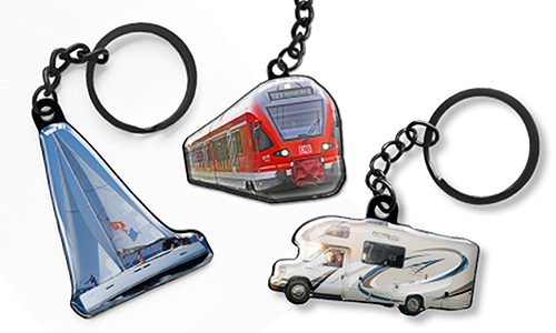 Sleutelhangers in de vorm van een zeilboot, een rode trein en een camper, gepresenteerd als aanpasbare reistoebehoren