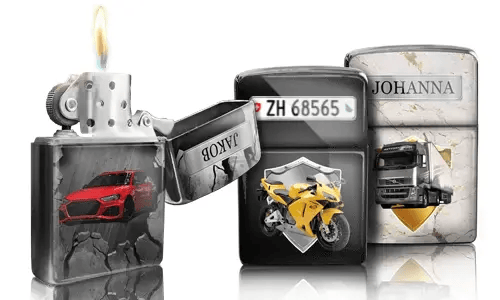 Drei metallische Feuerzeuge mit individuellen Designs: ein rotes Auto, ein gelbes Motorrad mit Kennzeichen und ein LKW mit der Aufschrift „JOHANNA“. Ein Feuerzeug ist geöffnet und die Flamme brennt.