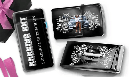 Drei schwarze Geldbörsen mit Auto-Designs. Eine trägt die Aufschrift „Burning Out ist meine Leidenschaft“, eine andere zeigt ein Auto mit Kolben und einer Person, und die dritte zeigt ein Auto mit karierten Flaggen und Kolben. In der Ecke liegt eine violette Schleife.