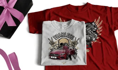 Zwei T-Shirts: weiß mit FEARLESS, Schädel, Heiligenschein, Handzeichen, rotem Auto; rot mit Flügelschädel