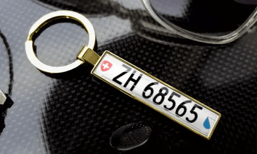 Gouden nummerplaat sleutelhanger toont gegraveerde tekst in een gepolijste metalen rand