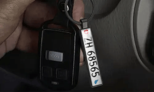 Silver license plate keychain hangs from car keys inside a vehicle