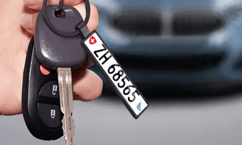 Zwarte nummerplaat sleutelhanger hangt aan autosleutels voor dagelijks gebruik