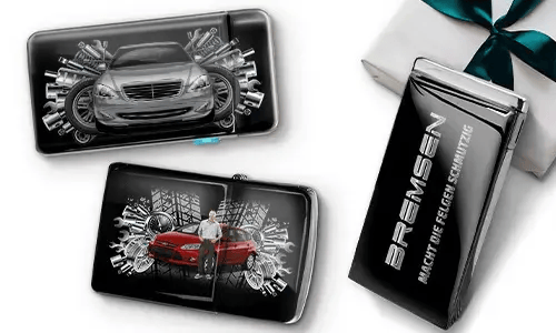 Drei elegante schwarze Geldbörsen mit Bildern von Autos und Zahnrädern, platziert neben einer Geschenkbox. Auf einer steht „Bremsen“. Das Design ist dynamisch und modern.