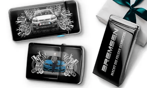 Three automotive-themed items featuring car illustrations and machinery motifs, arranged with a gift box tied with a green ribbon on the side.