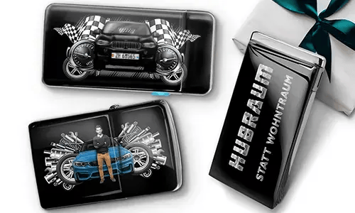 Geschenkset mit Auto-Themen-Metallbehältern, die Bilder eines grünen Sportwagens, karierten Flaggen und Motor-Motiven zeigen. Enthält ein Zigarettenetui mit der Aufschrift „Hubraum Statt Wohntraum“.