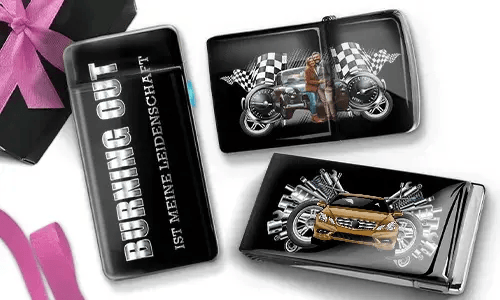 Drei glänzende Zigarettenetuis mit Automotiv. Eines trägt die Aufschrift „Burning Out Ist Meine Leidenschaft“. Die anderen zeigen ein Motorrad und ein Sportauto mit karierten Flaggen.