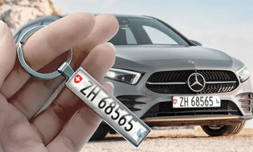 Comic-Kennzeichen-Schlüsselanhänger in der Hand gehalten, mit passendem Autokennzeichen im Hintergrund