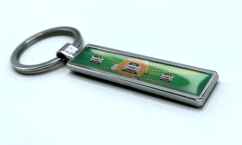 Metalen stripstijl autosleutelhanger met groene achtergrond en illustraties van sportvoertuigen