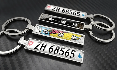 Comic-style license plate keychains arranged on a carbon-textured surface with colorful car graphics