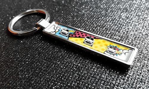 Metalen stripstijl autosleutelhanger met Pop-Art design en kleurrijke voertuigillustratie