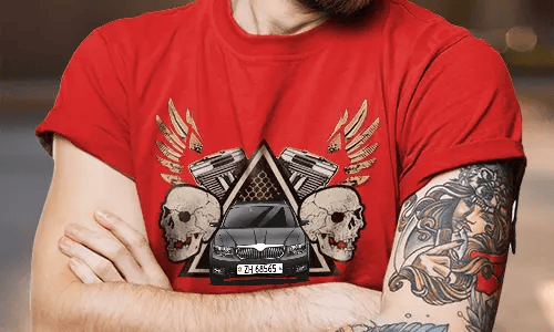 Rotes T-Shirt mit weißer SUV-Grafik, flankiert von Schädeln und Kolben, goldene Flügel dahinter, getragen von tätowierter Person