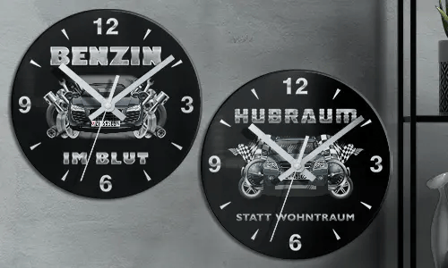 Zwei schwarze Wanduhren mit Autoillustrationen und deutschem Text: BENZIN IM BLUT und HUBRAUM STATT WOHNTRAUM